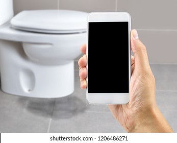 A Hand Holding A Smartphone To Call The Professional To Repair A Water Leak In The Toilet