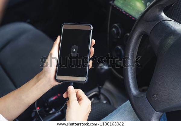 Hand\
holding smartphone and changing phone battery in\
car