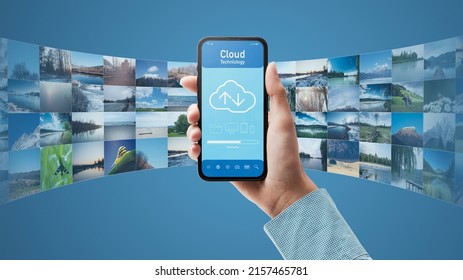 Hand holding a smartphone and cloud-based application, the user is downloading data on the device, POV shot