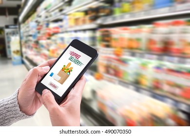 Hand Holding Smartphone With Delivery Service App On Screen And Fresh Food Supermarket Store Background