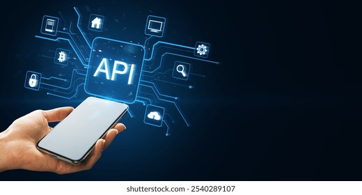 A hand holding a smartphone displaying holographic API icons connected to technology symbols on a dark blue, futuristic background. Concept of digital networking - Powered by Shutterstock