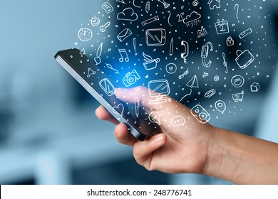 Hand holding smartphone with hand drawn media icons and symbols concept - Shutterstock ID 248776741