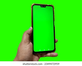 Hand holding smartphone with green screen background - Powered by Shutterstock