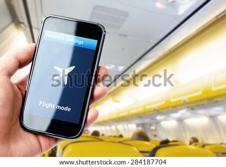 Hand holding smartphone inside the plane with flight mode activated