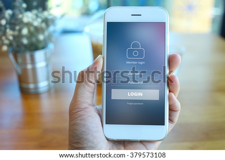 Hand holding smartphone with member loging screen on coffee shop background