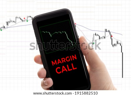 Hand holding a smartphone with the message margin call. Trading loss stock exchange. Brokerage account