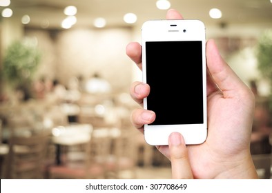 Hand Holding Smartphone Over Blur Restaurant Background, Restaurant Reservation, Food Online, Food Delivery Concept