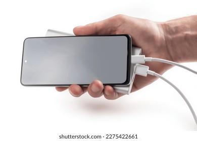 Hand holding smartphone with powerbank. Isolated on white