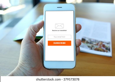 Hand holding smartphone with receive newsletter form on cafe background