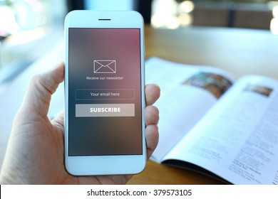 Hand holding smartphone with receive newsletter form screen on cafe background