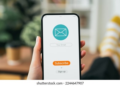 Hand holding smartphone and shows a digital screen of subscribe email notifications or sign up.