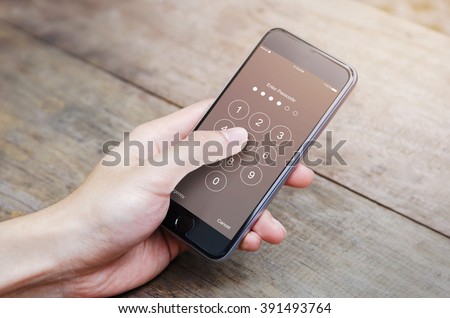 hand holding smartphone while entering the passcode.