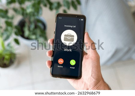 Hand holding smartphone while receiving incoming call from work.