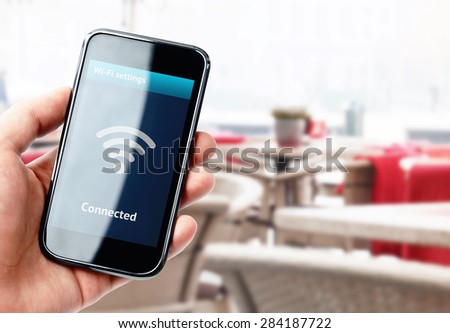 Hand holding smartphone with wi-fi connection on the screen in cafe