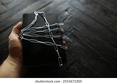 Hand Holding a Smartphone Wrapped in Chains - Concept of Digital Security and Restrictions
