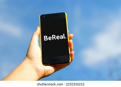 Hand holding smartphone in yellow plastic case  on blue sky nature background. Bereal app. BeReal is a new social media app and Photo sharing platform. Volodymyr, Ukraine, October 23, 2022. - Shutterstock ID 2232310215