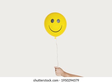 Hand Holding Smiling Face Yellow Balloon, Isolated On White Background