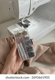 Hand Holding Snap Button Tool Kit in Front of a Sewing Machine