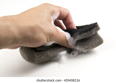 Hand Holding A Soapy Sponge With Scrub On A White Background