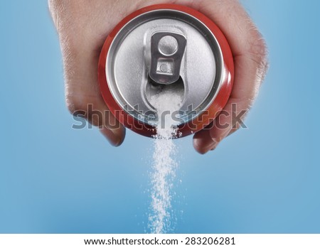 hand holding soda can pouring a crazy amount of sugar in metaphor of sugar content of a refresh drink isolated on blue background in healthy nutrition, diet and sweet addiction concept