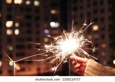 Hand holding sparkler. Sparkler with blurred busy city light background