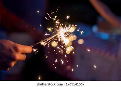 Hand holding a sparkler during blue hour in the backyard at a family celebration