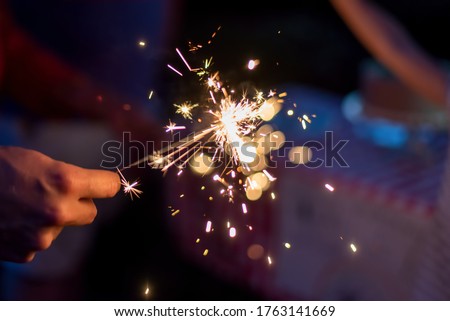 Hand holding a sparkler during blue hour in the backyard at a family celebration