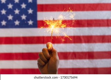 Hand Holding Sparkler In Front Of Usa Flag 