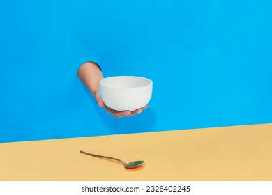 a hand is holding a spoon and a bowl - Powered by Shutterstock