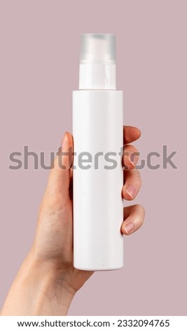 Hand holding spray bottle mockup, blank beauty product on pink background.