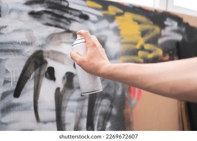 hand holding spray paint can, artist doing graffiti art on the wall