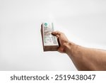 Hand Holding Spread of Egyptian 100 Pound Banknotes on White Background