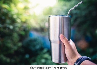 Hand holding a stainless steel tumbler / keeping the temperature of the drink cold or hot with copy space