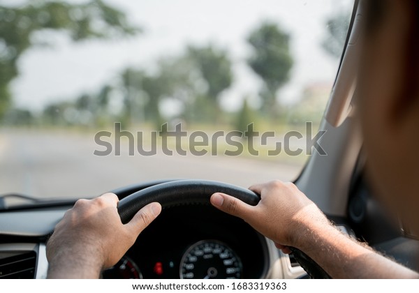 The hand is holding the steering wheel of the car\
Safe driving
