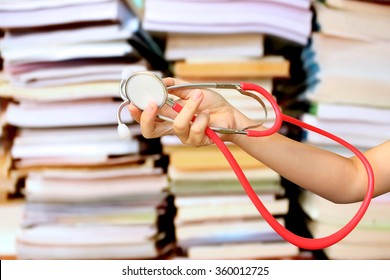 hand holding stethoscope on blur stacking book background