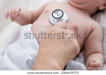 Hand holding stethoscope on newborn baby's chest