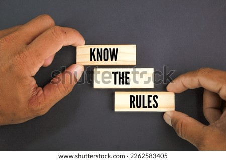 hand holding a stick with the words Know the rules. the concept of regulation. the concept of obeying the rules