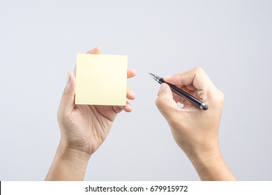 Hand holding sticky note paper sheet on white background