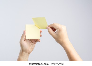 Hand holding sticky post note paper sheet on white background