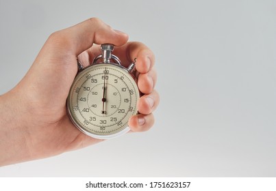 hand holding a stopwatch on a gray background