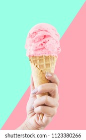 Hand Holding Strawberry Ice Cream Cone Isolated On Blue And Pink Background