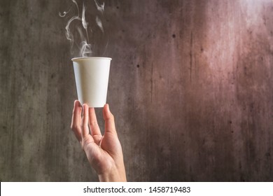 Hand Holding A Styrofoam Cup Of Hot Coffee On The Wooden Wall Background