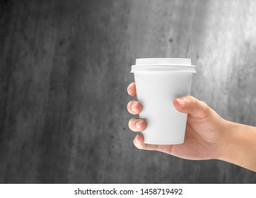 Hand Holding A Styrofoam Cup Of Hot Coffee On The Wooden Wall Background