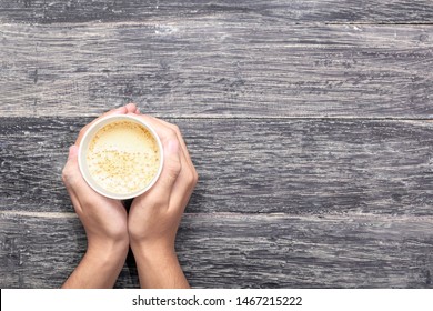 Hand Holding A Styrofoam Cup Of Hot Coffee Over Wooden Table Background