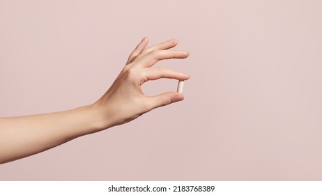 Hand holding the supplements on pink background. High quality photo