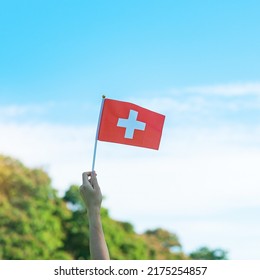hand holding Switzerland flag on blue sky background. Switzerland National Day and happy celebration concepts - Shutterstock ID 2175254857