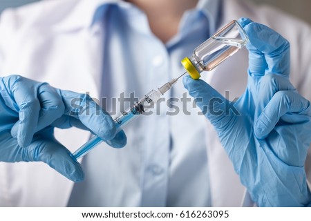 Hand holding syringe and vaccine.