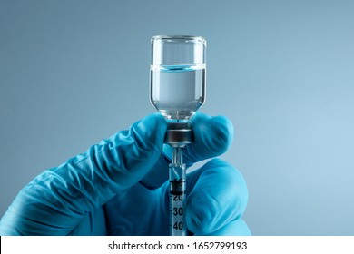 Hand holding syringe Vaccine in vial closeup on gray background, medical concept vaccination subcutaneous injection, dose. Disease treatment immunization