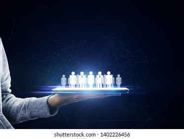 Hand holding tablet with glowing social network on dark background. Networking and HR concept