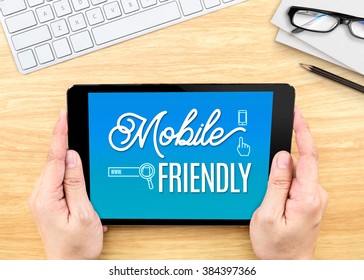 Hand Holding Tablet With Mobile Friendly Word On Wood Table ,Digital Marketing Concept